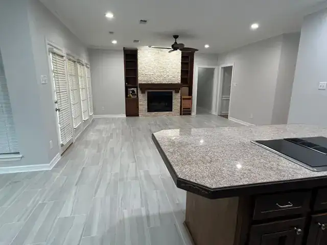 Open living and kitchen area with new tile flooring and a stone fireplace