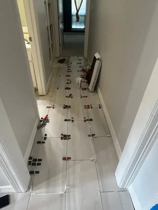 Tile installation in progress with levelling clips in a hallway