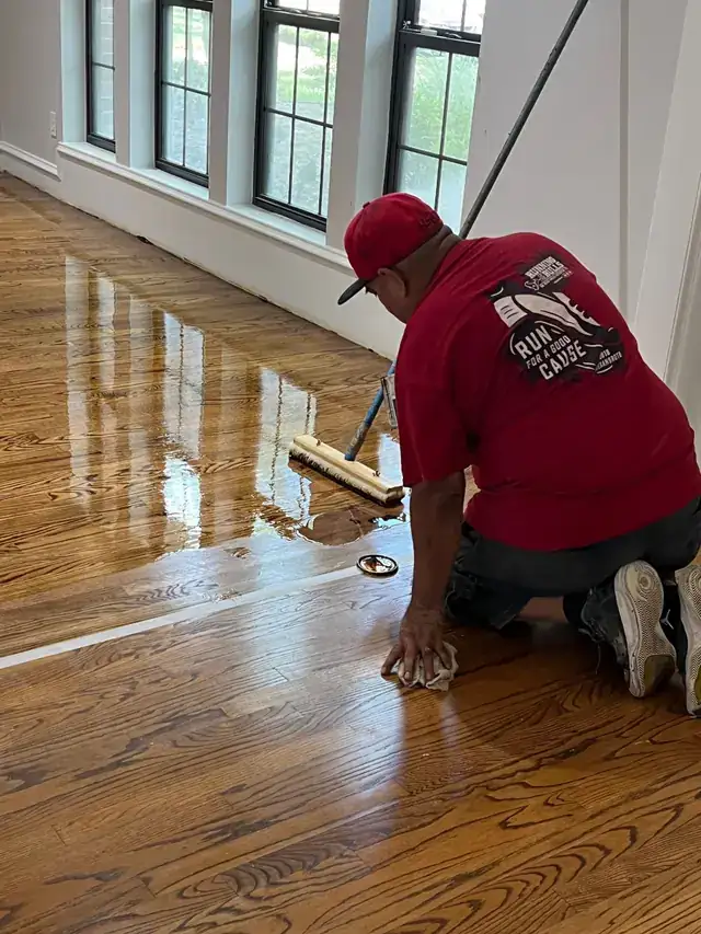 A ProRoofs crew member refinishing a hardwood floor